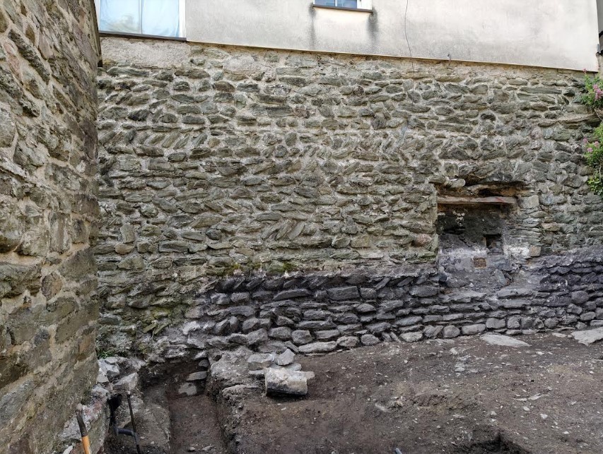A general photo showing the Roman wall extending down into the narrow trench. Image: Heneb: Gwynedd Archaeology